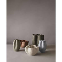 collection of fluid vases with wavy silhouettes in muted tones including pearl blue, beige, gray, and brown on a neutral background