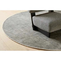 Round dove grey hand-woven GlobeWest Tepih Neptune rug under chair on wooden floor