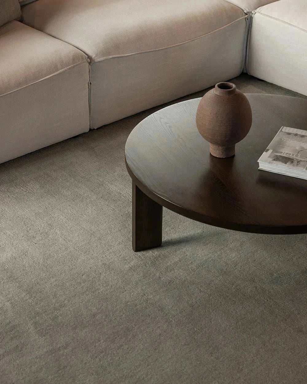 Baya Haywood Floor Rug in slate with velvet-like texture under dark wooden coffee table and beige sofa