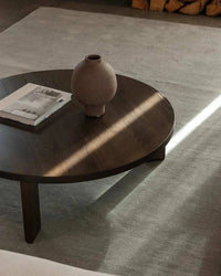 Baya Haywood Floor Rug in Slate color under round wooden coffee table with ceramic vase and magazine