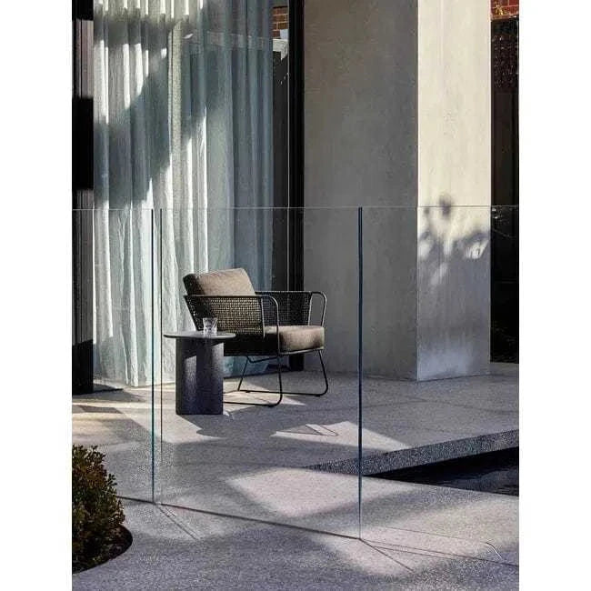 Black speckle Artie Outdoor Wave side table in fibrestone with wave design on a patio next to a cushioned chair