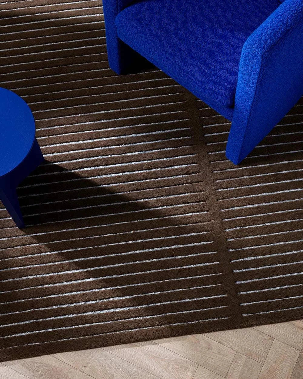 Baya Marlow Floor Rug in chocolate brown with linear high-low wool pile under blue chair and table