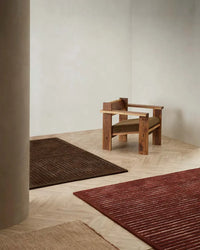 Baya Marlow Floor Rug in wine color with high-low pile wool texture on wooden floor next to wooden armchair