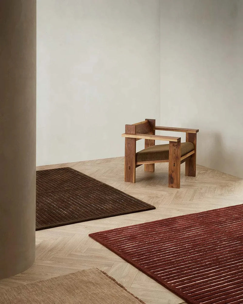 Baya Marlow Floor Rug in wine color with high-low pile wool texture on wooden floor next to wooden armchair