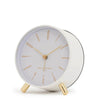 Maya Silent Alarm Clock in white with gold numerals, hands, and feet, featuring silent sweep movement and built-in nightlight.