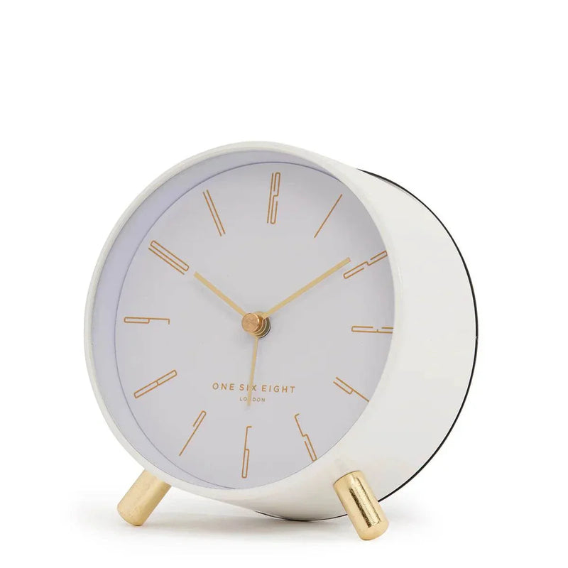 Maya Silent Alarm Clock in white with gold numerals, hands, and feet, featuring silent sweep movement and built-in nightlight.