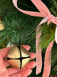 norsu STUDIO Handcrafted oversized gold bell decoration held against a Christmas tree with pink velvet ribbon