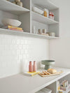 minimalist styled kitchen shelves with decorative bowls, mugs, books, and cutting board displaying bread and jars, showcasing how to style your shelves