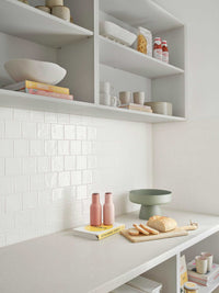 minimalist styled kitchen shelves with decorative bowls, mugs, books, and cutting board displaying bread and jars, showcasing how to style your shelves