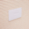 Close-up of woven polypropylene straw texture with white leather Base Supply Panier logo patch on chalk crossbody bag
