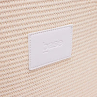 Close-up of woven polypropylene straw texture with white leather Base Supply Panier logo patch on chalk crossbody bag