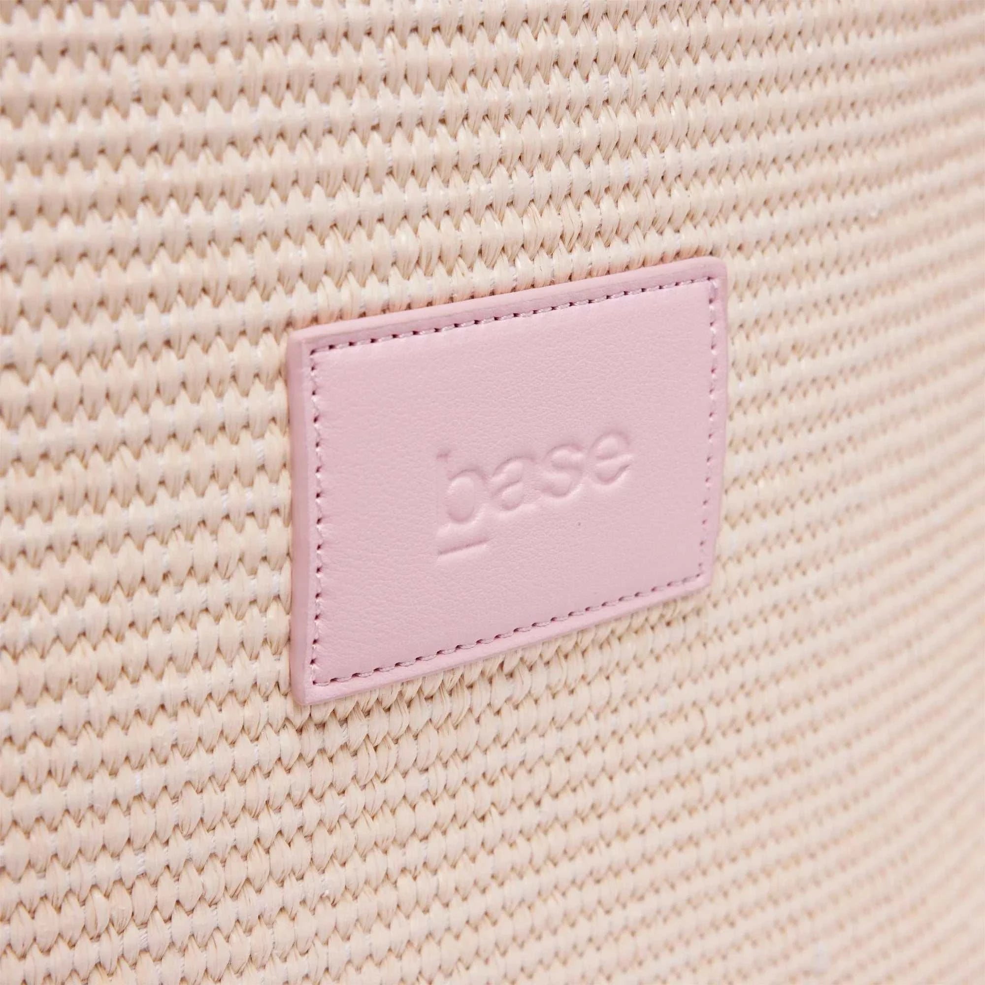 Close-up of Base Supply Panier Crossbody bag in pink showing woven straw texture and pink logo patch