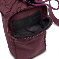Base Supply Bottle Sling crossbody bag in burgundy with waterproof soft fabric and zippered pocket.