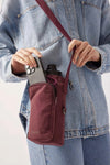burgundy Base Supply Bottle Sling crossbody bag with adjustable strap holding water bottle and phone
