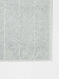 Paros Bath Mat in limestone color made from sustainable cotton with a soft, absorbent texture and simple striped design.