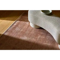 GlobeWest Tepih Neptune Rug in Dusty Rose hand-woven wool blend with subtle rustic texture placed on wooden floor under modern curved furniture