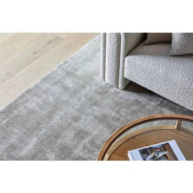 GlobeWest Tepih Tide Rug in oyster color with ripple ocean design placed in modern living room with neutral furniture and wooden table