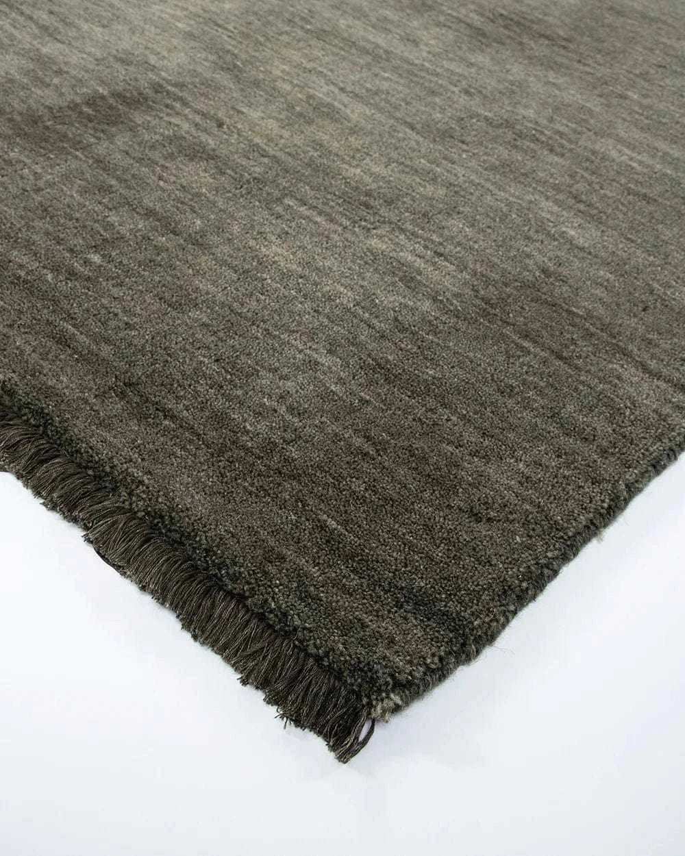 Close-up of the Sandringham Floor Rug in forest green with handknotted wool pile and fringed edges.