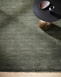 Forest green Sandringham Floor Rug with handknotted wool pile and subtle fringing under a modern round table.