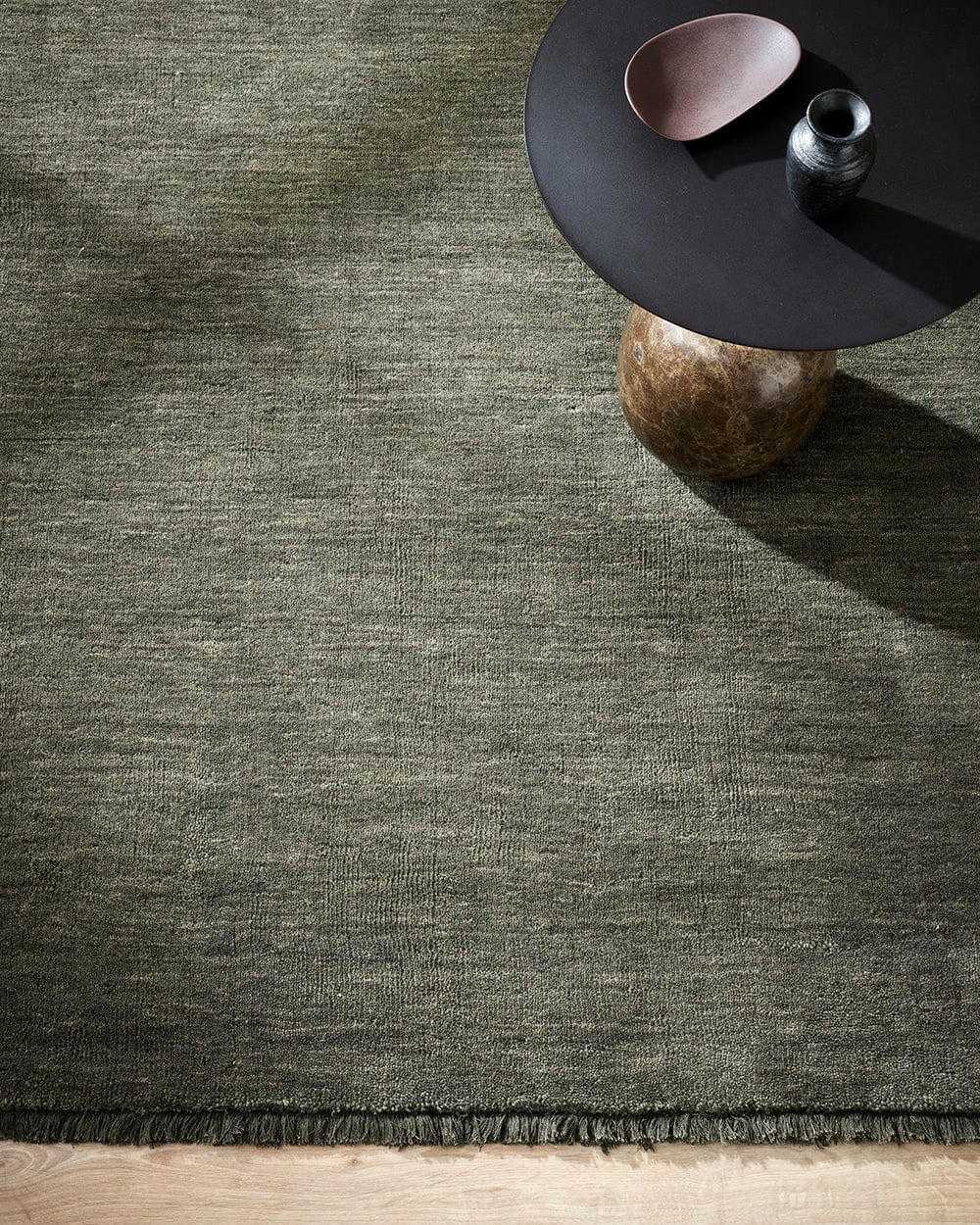 Forest green Sandringham Floor Rug with handknotted wool pile and subtle fringing under a modern round table.