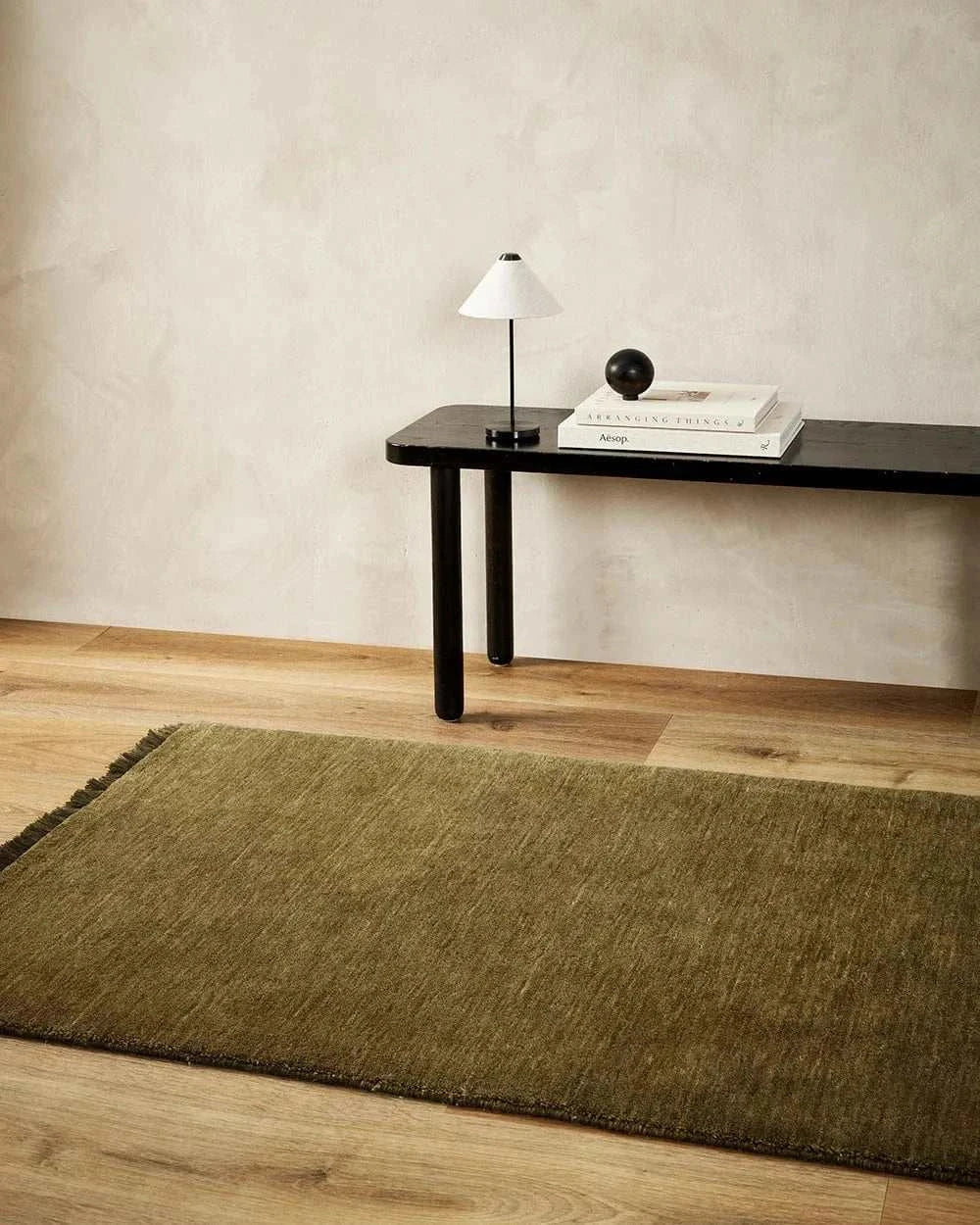 Sandringham Moss Floor Runner 0.9m x 5m wool rug in moss green with soft texture on wooden floor near black console table