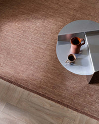 Baya Sandringham Floor Rug in rosewood shade with dense wool pile and delicate fringes under modern table on wooden floor