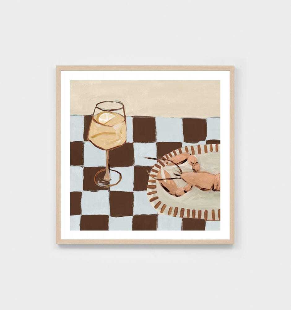 Still life print of a wine glass and lobster on a checkered table from Middle of Nowhere collection with white border and oak frame