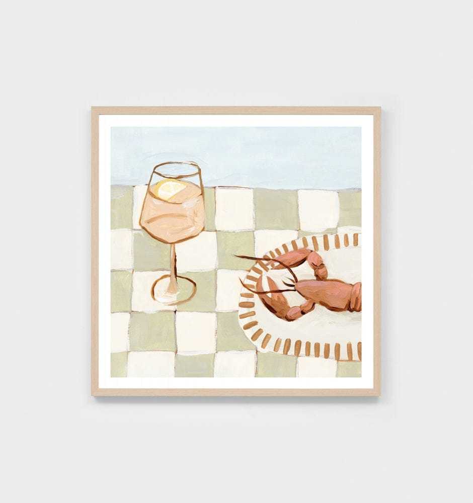 Middle of Nowhere seaside dining print featuring a glass with a lemon slice and a lobster on a checkered tablecloth in sage tones with a wooden frame