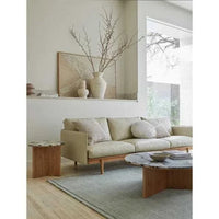 Living room with GlobeWest Bower Frame Rug in seafoam, beige sofa, wooden side table, and marble coffee table under natural light
