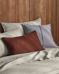 Sova Savanna linen pillowcases layered with cushions on a made bed