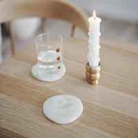 Black Blaze white onyx marble coaster set on wooden table with candle and glass