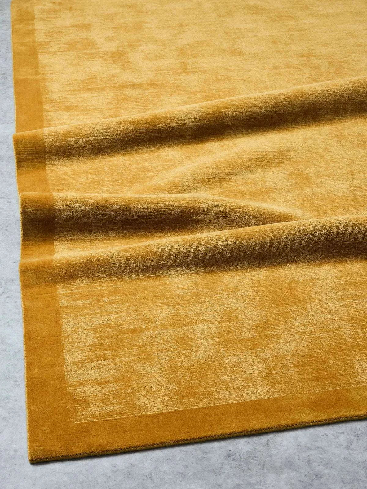 Tait Rug in vibrant turmeric color, hand-loomed wool with textured finish