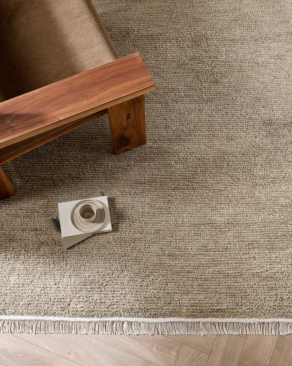 Baya Tanami Floor Rug in fossil taupe with hand-knotted texture and soft cotton fringe under wooden furniture