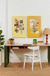 Two mustard yellow magnetic storyboards mounted on a white brick wall above a wooden desk with a white chair, next to a red lamp and green plant, perfect for organizing plans and matching Mustard Made lockers.