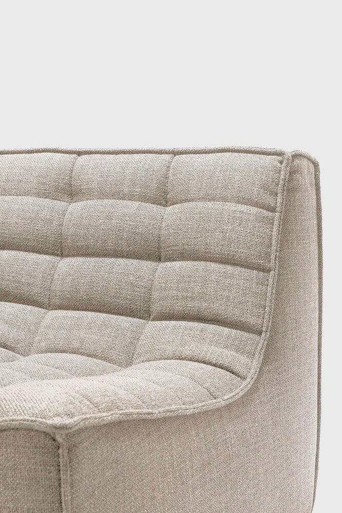 Close-up of Ethnicraft Sofa N701 in dark beige fabric with cushioned, tufted upholstery and curved edges.