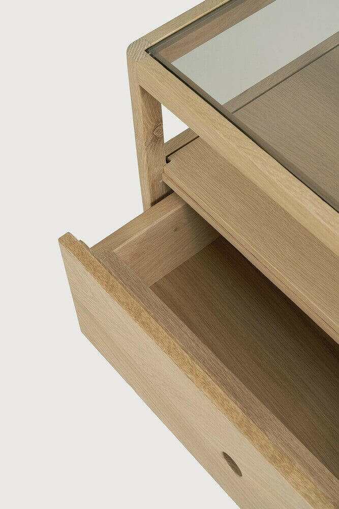 Ethnicraft Spindle Bedside table in natural oak with smokey glass top and single drawer open showing wood grain detail