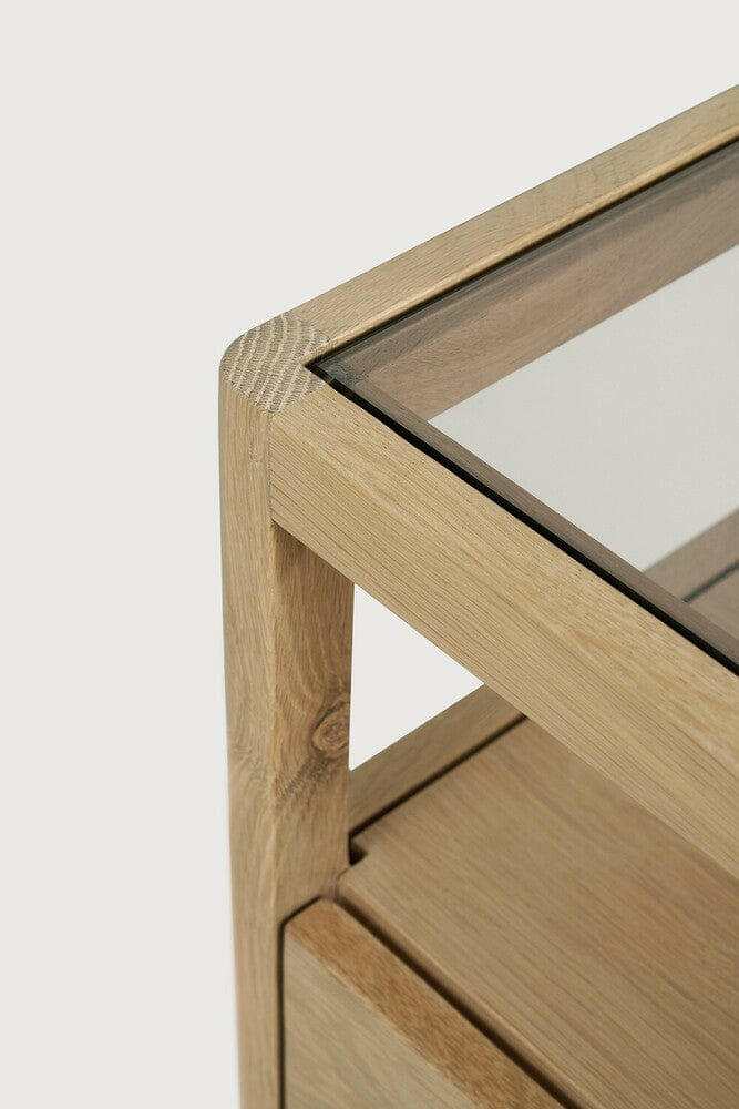Close-up of Ethnicraft Spindle Bedside table corner showing natural oak frame and smokey glass top