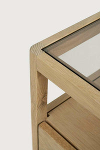 Close-up of Ethnicraft Spindle Bedside table corner showing natural oak frame and smokey glass top