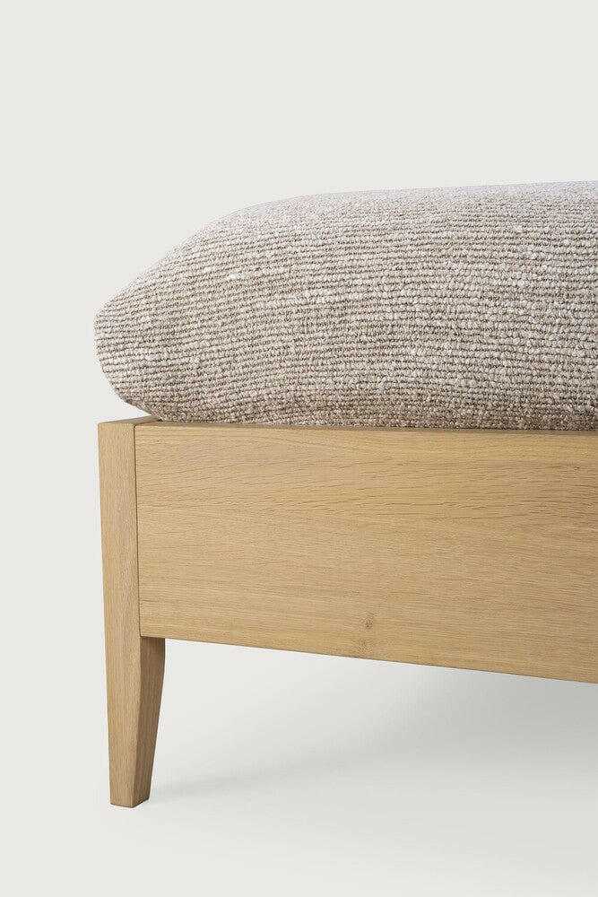 Close-up of Ethnicraft Spindle Bed made from natural oak with tapered legs and fabric mattress corner visible