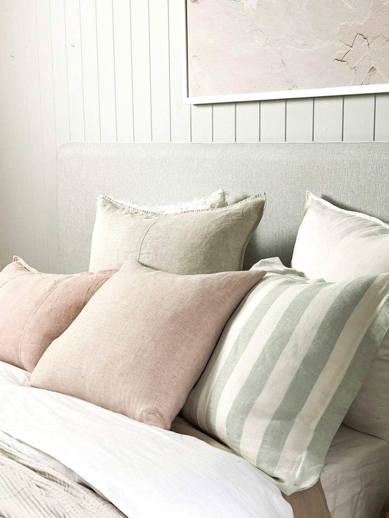 norsu Studio Washable Cushion in blush tone on bed with neutral pillows
