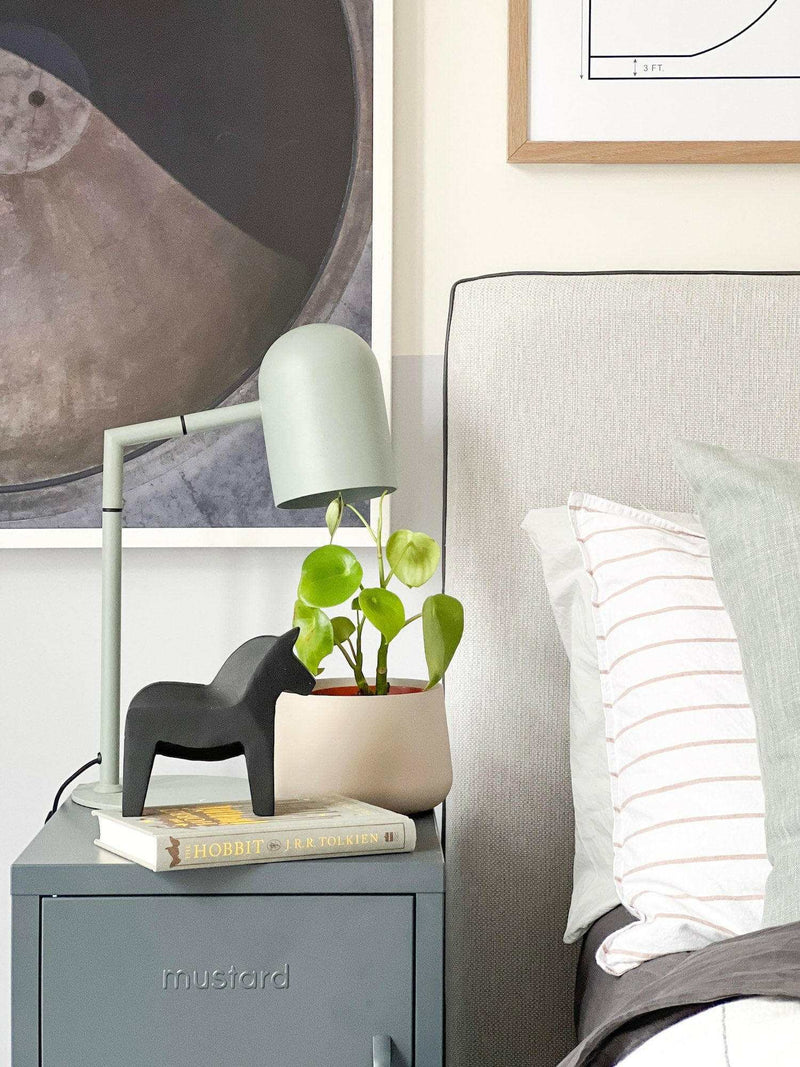 Sage green Pia desk lamp on bedside table with modern decor and plant