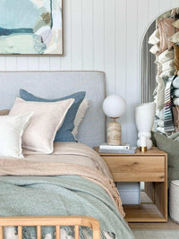 Baya Flaxmill Cushion nude linen on bed with blue and white pillows in cozy bedroom setting