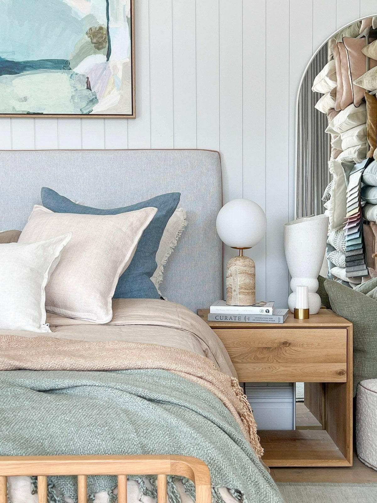 Baya Flaxmill Cushion nude linen on bed with blue and white pillows in cozy bedroom setting