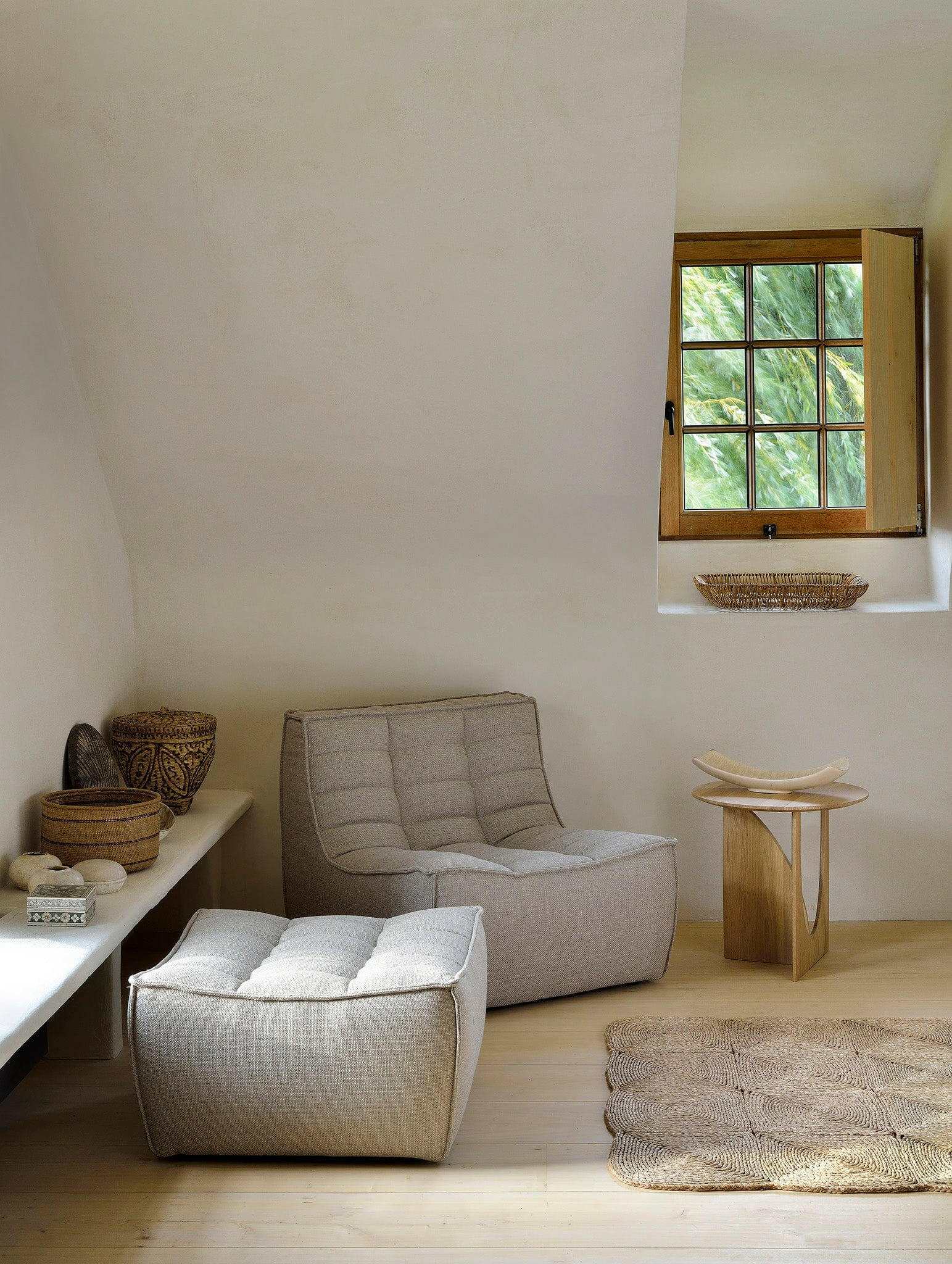 Ethnicraft Sofa N701 1-seater dark beige fabric armchair with ottoman in a minimalist natural room setting