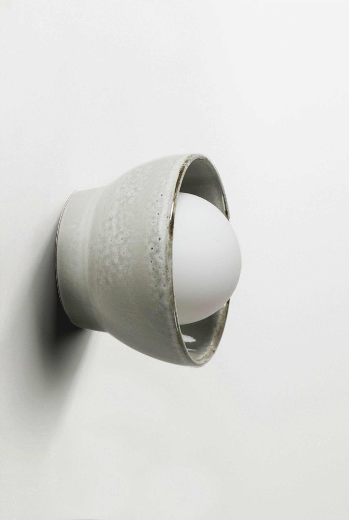 Robert Gordon Bowl Sconce ceramic wall light with halogen globe in saltbush finish mounted on white wall