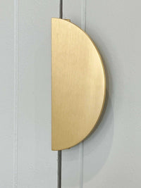 norsu Studio Solid Brass half moon door handle in brushed gold finish mounted on a light gray door