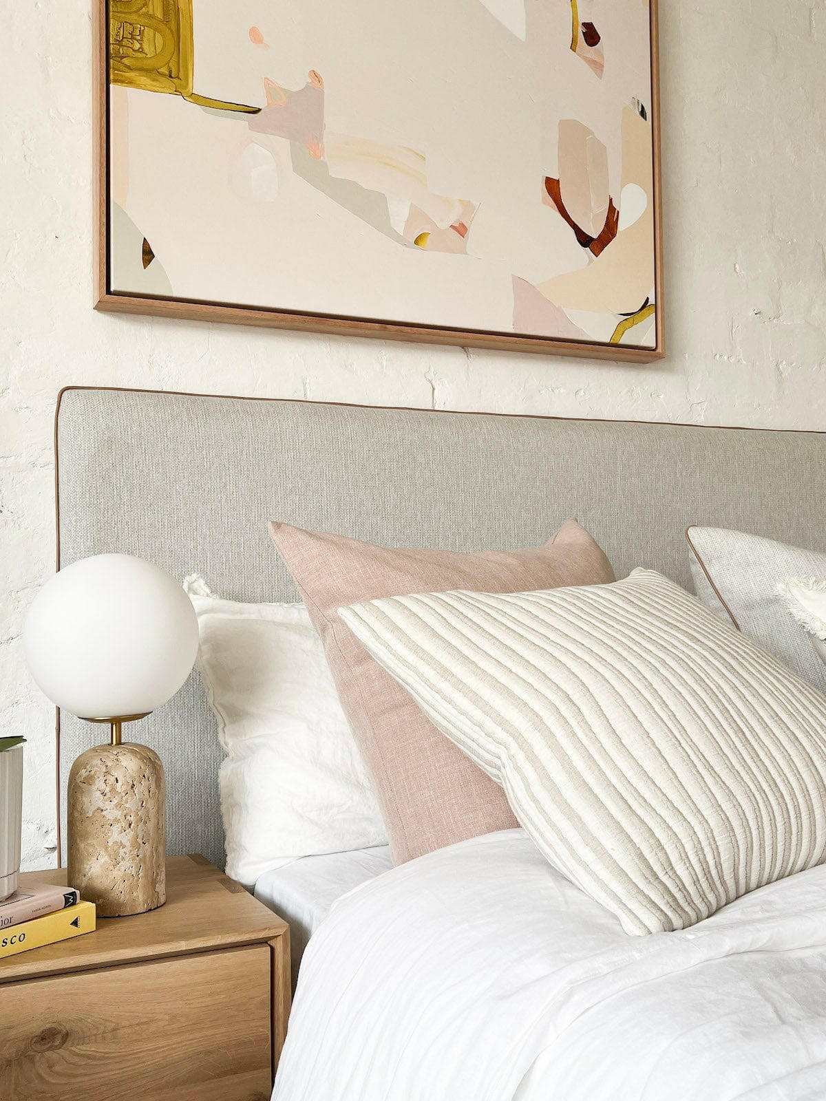 norsu Studio Washable Cushion in blush on bed with textured white cushion and bedside decor