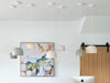 Set of large ceramic Robert Gordon Bell Light pendant lamps in neutral tones hanging from ceiling in modern room with artwork and wooden door