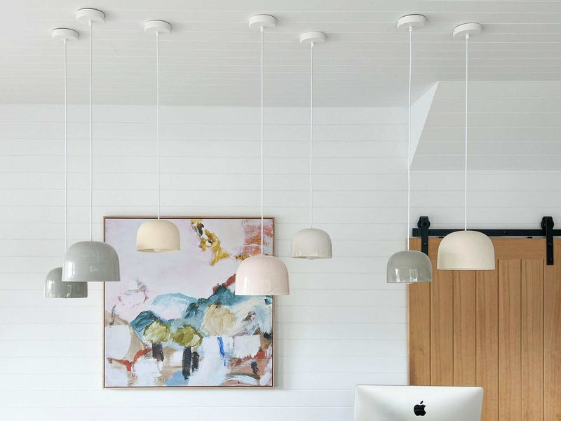 Set of large ceramic Robert Gordon Bell Light pendant lamps in neutral tones hanging from ceiling in modern room with artwork and wooden door