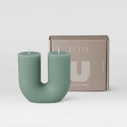 Modern green U-shaped Black Blaze candles with ribbed texture beside branded packaging box
